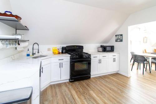 a kitchen with white cabinets and a black stove at Chi-Town Hideout #2 - Near Metra in Berwyn