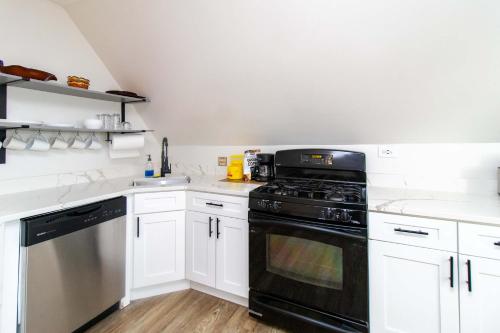 a kitchen with white cabinets and a black oven at Chi-Town Hideout #2 - Near Metra in Berwyn