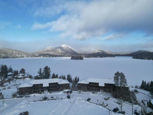 a resort in the snow with a lake and mountains at Escapade Bonheur in Lac-Superieur