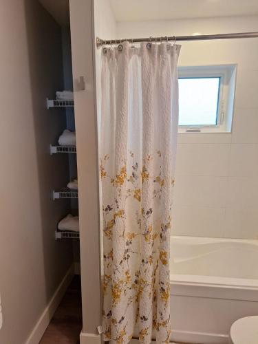 a shower curtain in a bathroom with a tub at Happy Zone Suite With AC- Sleeps 4 - Welcome Snacks & Drinks ! in Langford