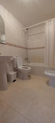 a white bathroom with a toilet and a sink at Casa Karina in Parque Holandes