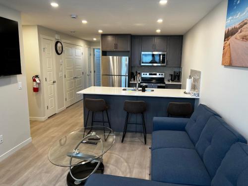 a living room with a blue couch and a kitchen at The Oasis-A New 1 bed suite in Livingston Calgary close to the Airport in Calgary