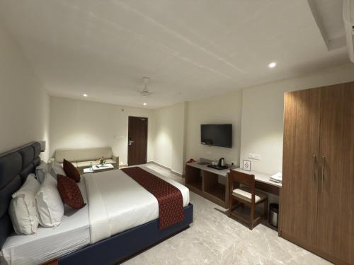 a hotel room with a bed and a desk and a television at Hotel Maritan - Hitech City, Hyderabad in Hyderabad