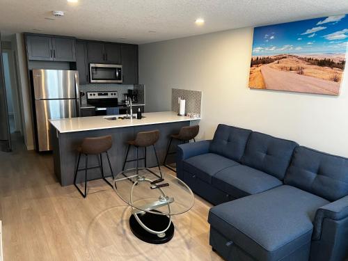 a living room with a blue couch and a kitchen at The Oasis-A New 1 bed suite in Livingston Calgary close to the Airport in Calgary