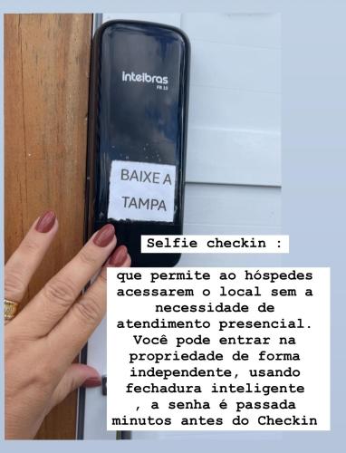a person holding a cell phone in front of a door at Cabana Monte Trigo in São Francisco do Sul