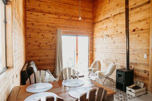a dining room with wooden walls and a table and chairs at Chalés Bosque das Oliveiras in Urubici
