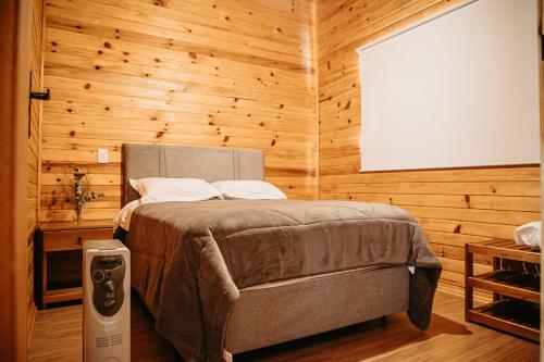 a bedroom with a bed in a wooden wall at Chalés Bosque das Oliveiras in Urubici