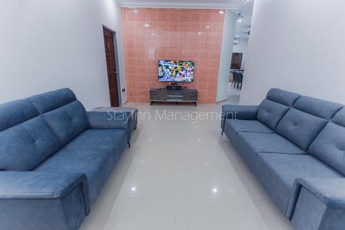 a living room with two blue couches and a tv at PD 4R3BR 20pax Private Pool Near To the beach in Port Dickson