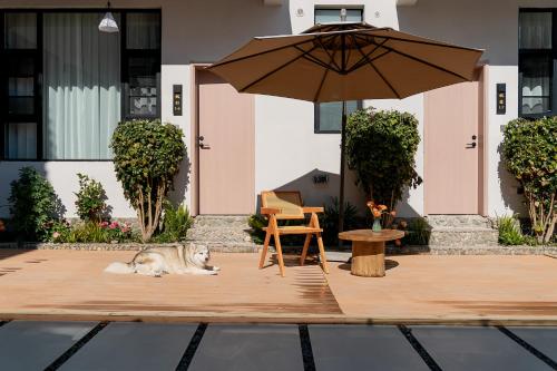 a dog laying on a wooden deck with an umbrella at Wuyi Whispering Maple in Dali