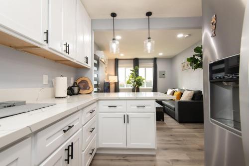 a kitchen with white cabinets and a living room at Spacious 3 Bedroom 2 Bathroom Apartment with Free Onsite Parking in Los Angeles