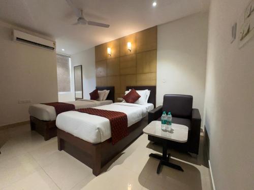 a hotel room with two beds and a chair at Hotel Maritan - Hitech City, Hyderabad in Hyderabad