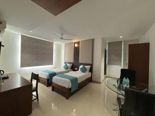 a hotel room with two beds and a desk at Hotel Maritan - Hitech City, Hyderabad in Hyderabad