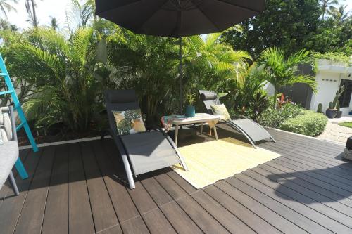 a patio with two chairs and an umbrella at Villa Beau Rivage in Bachok