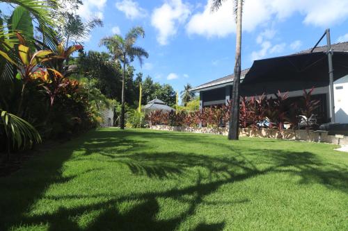 a green lawn with a palm tree in front of a building at Villa Beau Rivage in Bachok