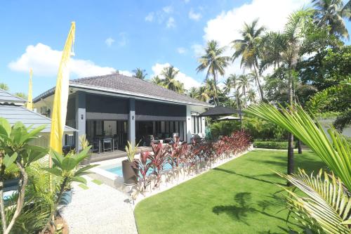 a house with a row of chairs in the yard at Villa Beau Rivage in Bachok