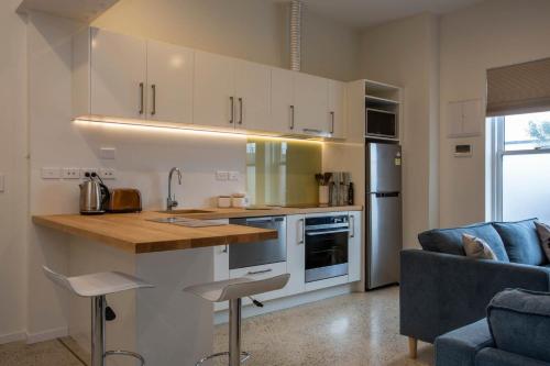 a kitchen with white cabinets and a blue couch at Cumberland Street deluxe apartment No1 in Dunedin