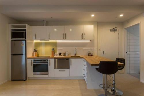 ダニーデンにあるCumberland Street deluxe apartment No2の白いキャビネットと木製のカウンタートップを備えたキッチン