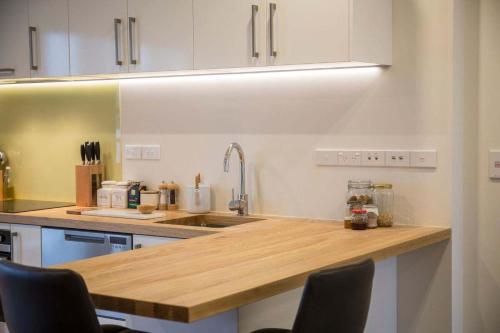 a kitchen with white cabinets and a wooden counter top at Cumberland Street deluxe apartment No5 in Dunedin