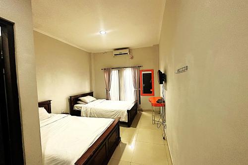 una camera d'albergo con due letti e una finestra di Hotel Warta Dua a Denpasar