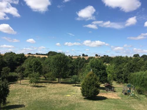a field with trees and a blue sky with clouds at Country-side house close to loire-valley castles in Sargé-sur-Braye