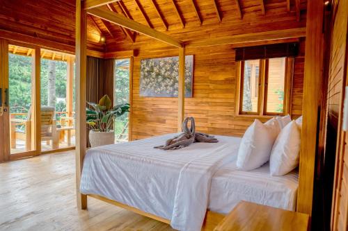 a bedroom with a bed in a room with wooden walls at Taman Swarga Villa Resort & Spa Sidemen in Sidemen