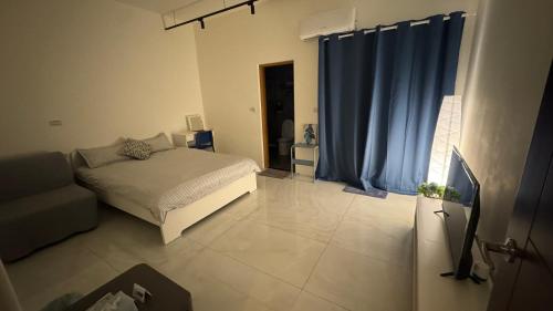 a bedroom with a bed and a couch and blue curtains at 小清新民宿 in Guangrong