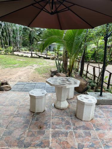 a table and two stools on a patio with an umbrella at Baan Namthip Homestay Trang บ้านน้าทิพย์ โฮมสเตย์ตรัง in Ban Huai To (1)