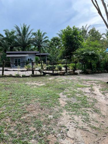 a house with a fence in front of a yard at Baan Namthip Homestay Trang บ้านน้าทิพย์ โฮมสเตย์ตรัง in Ban Huai To (1)