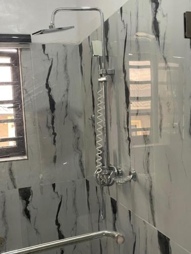 a shower in a bathroom with a black marble wall at Extravaganza Stay in Lagos