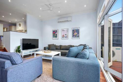 a living room with two blue couches and a tv at Bowen Street Family Retreat with Pool in Melbourne