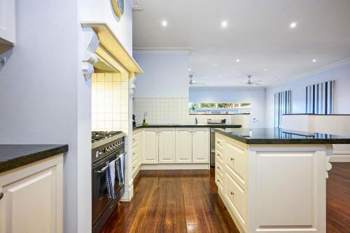 a large kitchen with white cabinets and black appliances at Bowen Street Family Retreat with Pool in Melbourne