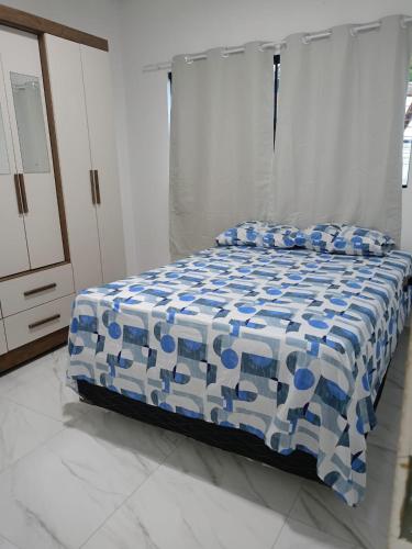 a bedroom with a bed with a blue and white comforter at Casa de Maria Praia Suape in Cabo de Santo Agostinho