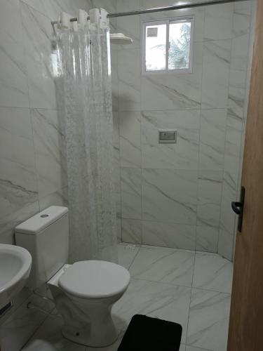 a white bathroom with a toilet and a shower at Casa de Maria Praia Suape in Cabo de Santo Agostinho