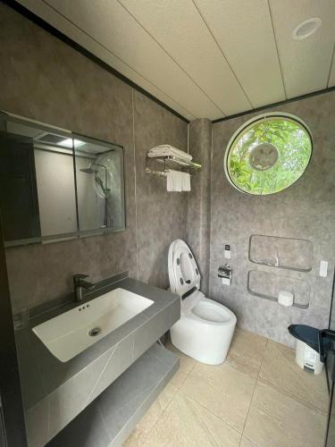 a bathroom with a white toilet and a sink at Halo Retreat in Hòa Bình