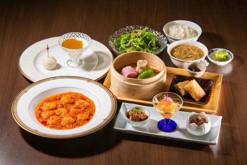 a table with plates of food and bowls of food at Loisir Spa Tower Naha in Naha