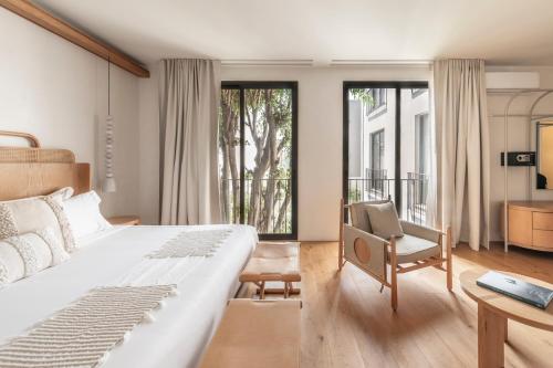 a bedroom with a bed and a chair and windows at Casa Ofelia in Mexico City