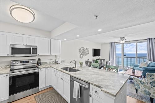 cocina con armarios blancos y vistas al océano en Pelican Beach Resort 809, en Destin