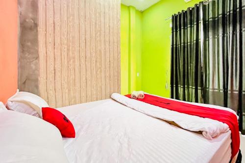 a bedroom with a bed with red and white pillows at RedDoorz at MCLOS Syariah Guest House Rantau Perapat in Rantauprapat