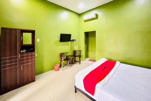 a bedroom with green walls and a bed with a red blanket at RedDoorz at MCLOS Syariah Guest House Rantau Perapat in Rantauprapat