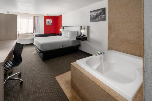 a hotel room with a bed and a bath tub at SYLO Hotel Denver Airport, a Ramada by Wyndham in Aurora