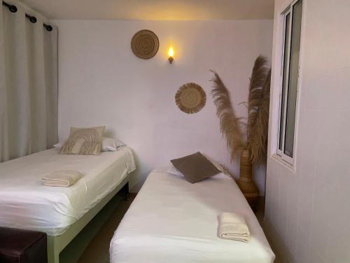 two beds in a room with white walls at Hermoso Apartamento cerca a la playa in Cartagena de Indias