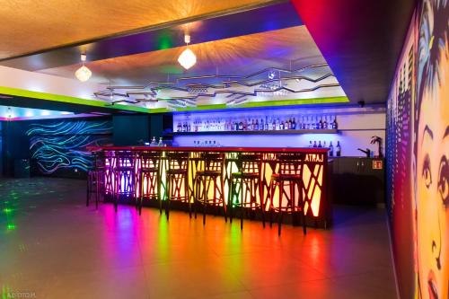 a nightclub with a bar with colorful lights on the wall at Pensjonat & Spa Raj in Rajgród