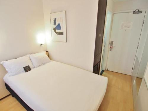 a small bedroom with a white bed and a door at ibis Hong Kong North Point in Hong Kong