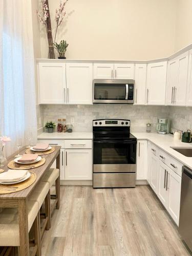 a kitchen with white cabinets and a stove and a table at Central 2BR Near Yale WiFi with Washer and Dryer in New Haven