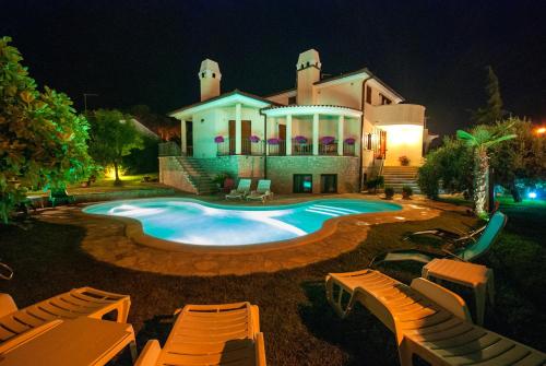 a large house with a swimming pool at night at Guesthouse Villa Lena in Premantura