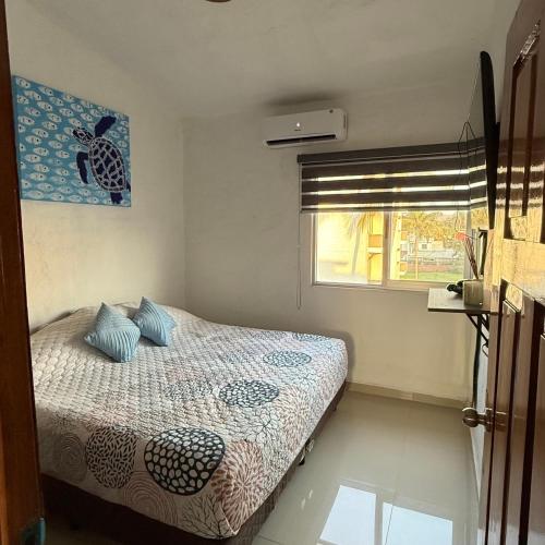 a bedroom with a bed and a window at Departamento en suites palmas, con club de playa in Manzanillo