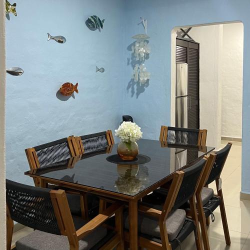 a dining room table with chairs and a vase of flowers at Departamento en suites palmas, con club de playa in Manzanillo