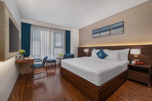 a hotel room with a large bed and a desk at Canvas Danang Beach Hotel in Da Nang