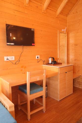 a wooden room with a desk and a tv on a wall at The Auli Meadows in Joshīmath