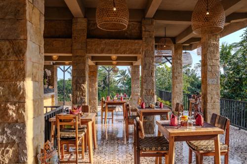 a restaurant with wooden tables and chairs at Hoshi Jungle Resort in Tegalalang